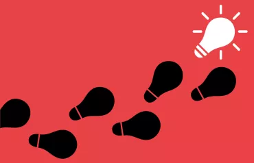 Image of light bulbs appearing as footprints on a path leading to a lit light bulb indicating a new idea.